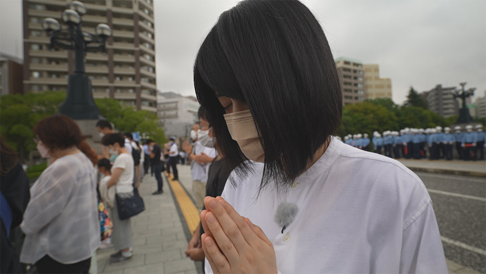 爆心地近くの橋で手を合わせる小松美羽